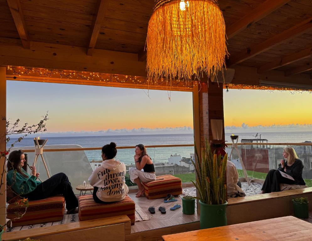 a group of people sitting on a porch with a view of the ocean at Taghazout Life in Taghazout
