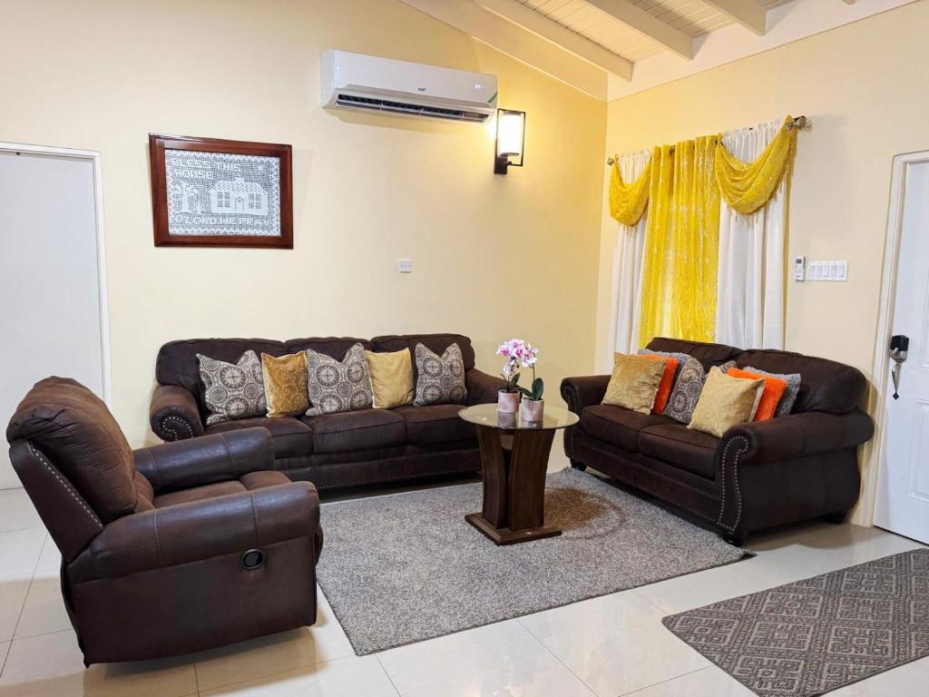 a living room with two leather couches and a table at L&V Paradise Vacation Home with Pool and Gym in Falmouth