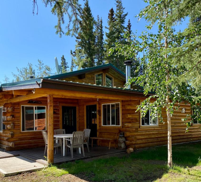 a log cabin with a table and chairs on the porch at Burnt Paw in Tok