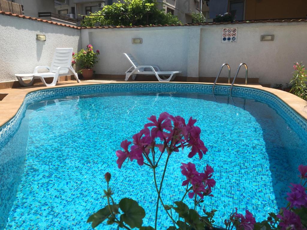 a swimming pool with blue water and purple flowers at Villa Diana in Sozopol