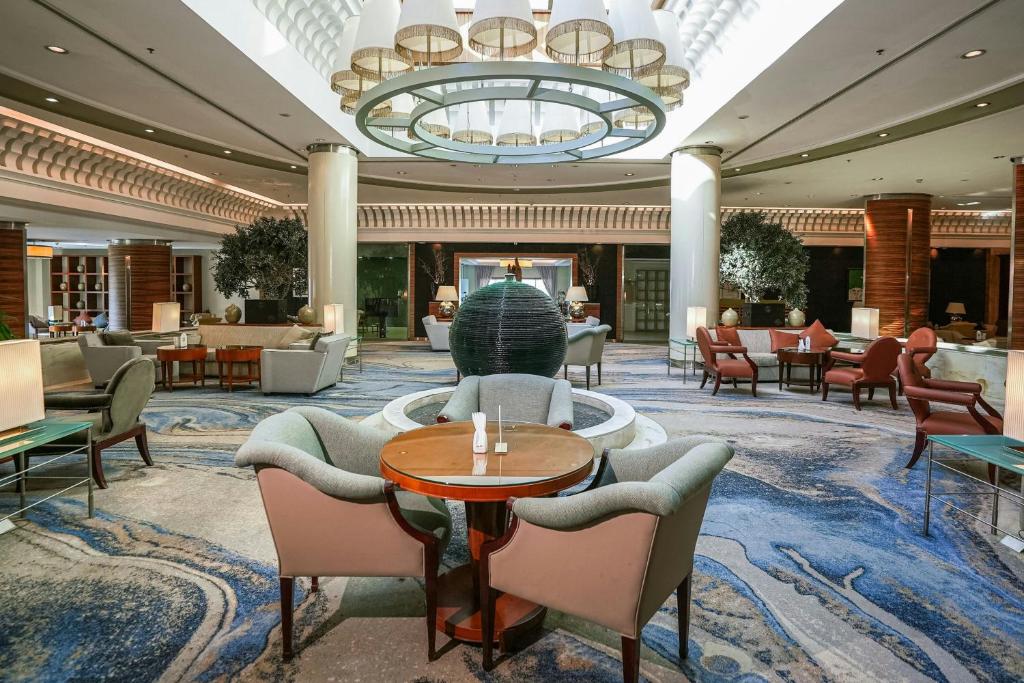 un vestíbulo con sillas, mesas y una lámpara de araña en Sheraton Dammam Hotel &amp; Convention Centre, en Dammam