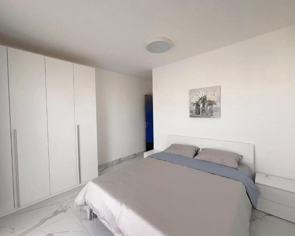 een witte slaapkamer met een bed en witte kasten bij Great flats in Wrocław