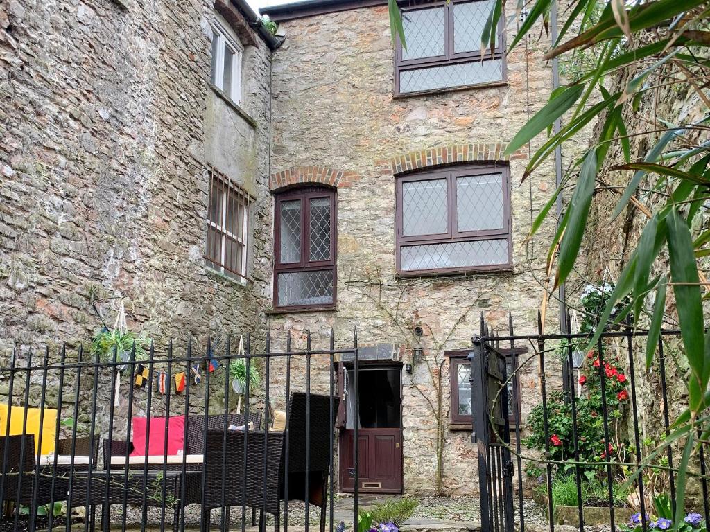 an old brick building with a fence in front of it at Fisherman's Cottage in Plymouth
