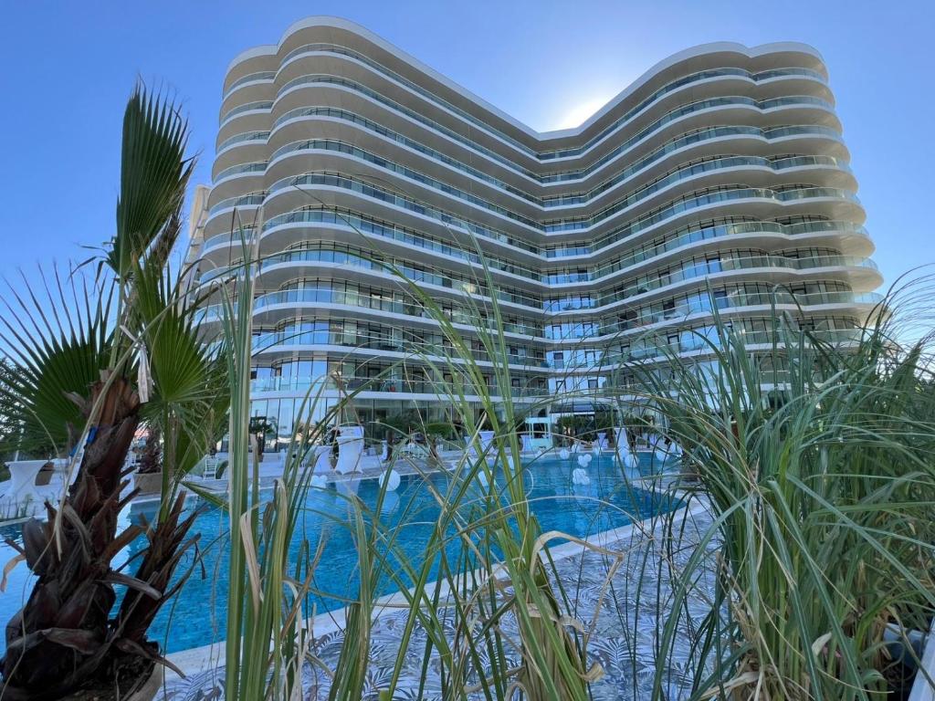 ein hohes Gebäude mit Pool davor in der Unterkunft White Sea Studio Premium in Mamaia Nord – Năvodari