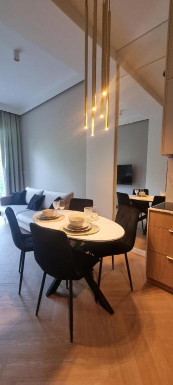 ein Esszimmer mit Tisch und Stühlen und einer Couch in der Unterkunft Omega Lake Apartments Nr 60 in Olsztyn