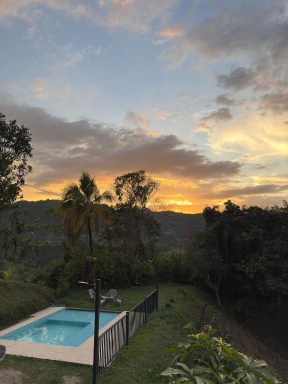 a swimming pool with a sunset in the background at Jaragual EcoHotel in La Vega