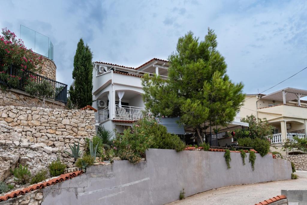a white house with a stone wall and trees at Apartments with parking space Vidalici, Pag - 9393 in Kustići