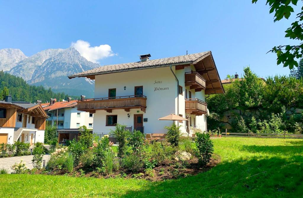 a house in a field with mountains in the background at Haus Widmann in Scheffau am Wilden Kaiser