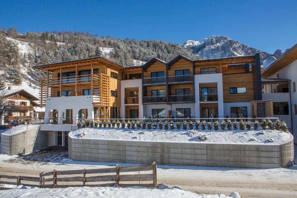 a large building in the snow with a mountain at Mölgg Dolomites Residence in San Vigilio Di Marebbe