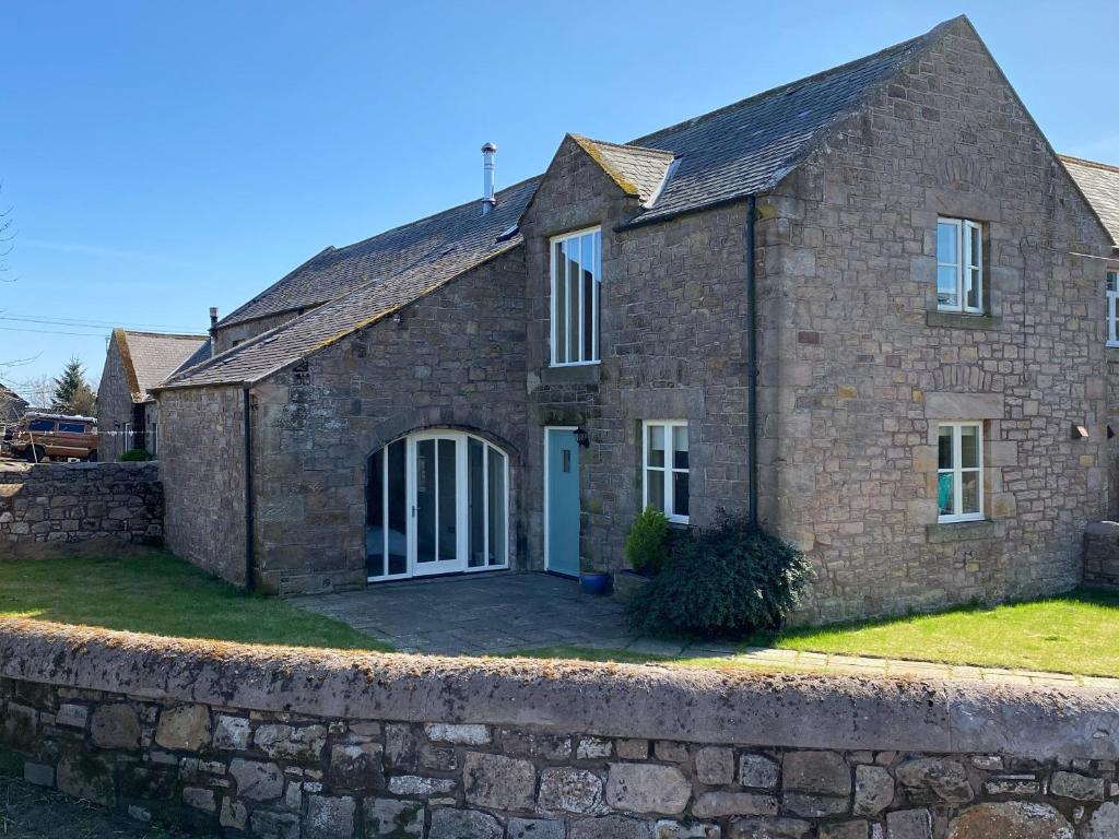 una antigua casa de piedra con un muro de piedra en 4 Murton Whitehouse Steading, en East Ord