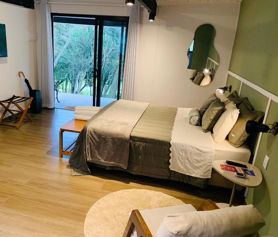 a bedroom with a bed and a large window at Bangalô 2 Rota do Vinho São Roque in São Roque