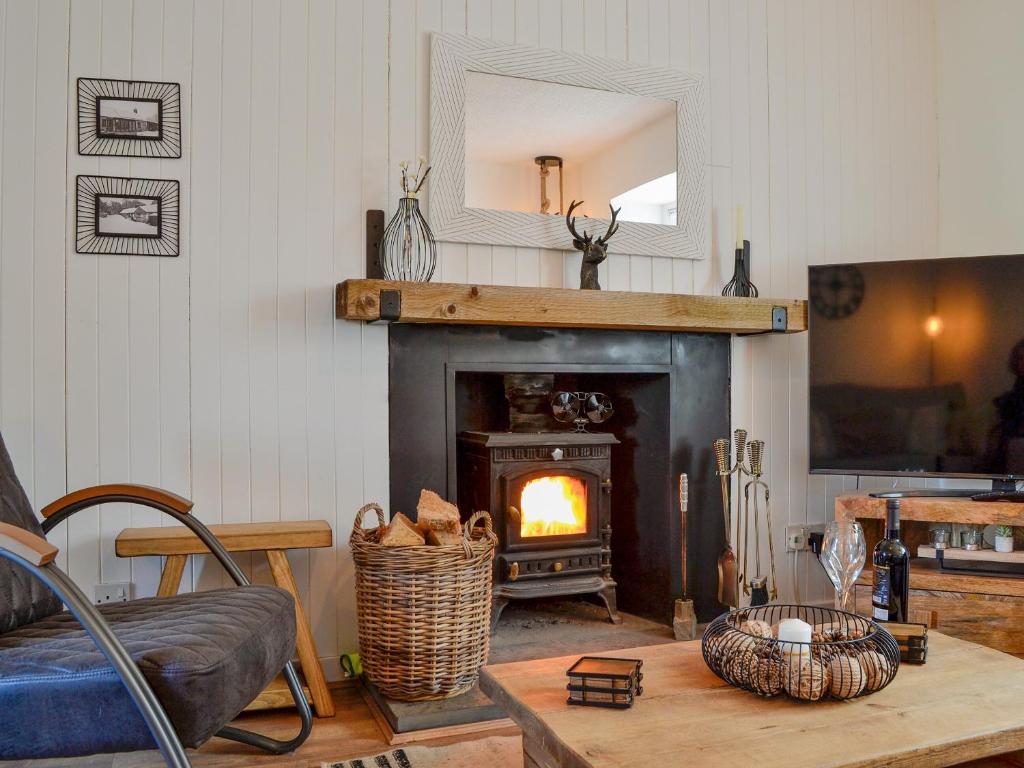 a living room with a fireplace and a mirror at Black Spout Cottage in Moulin