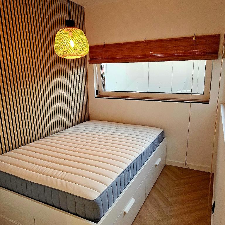 a small bed in a room with a window at Apartament Contandair in Olsztyn