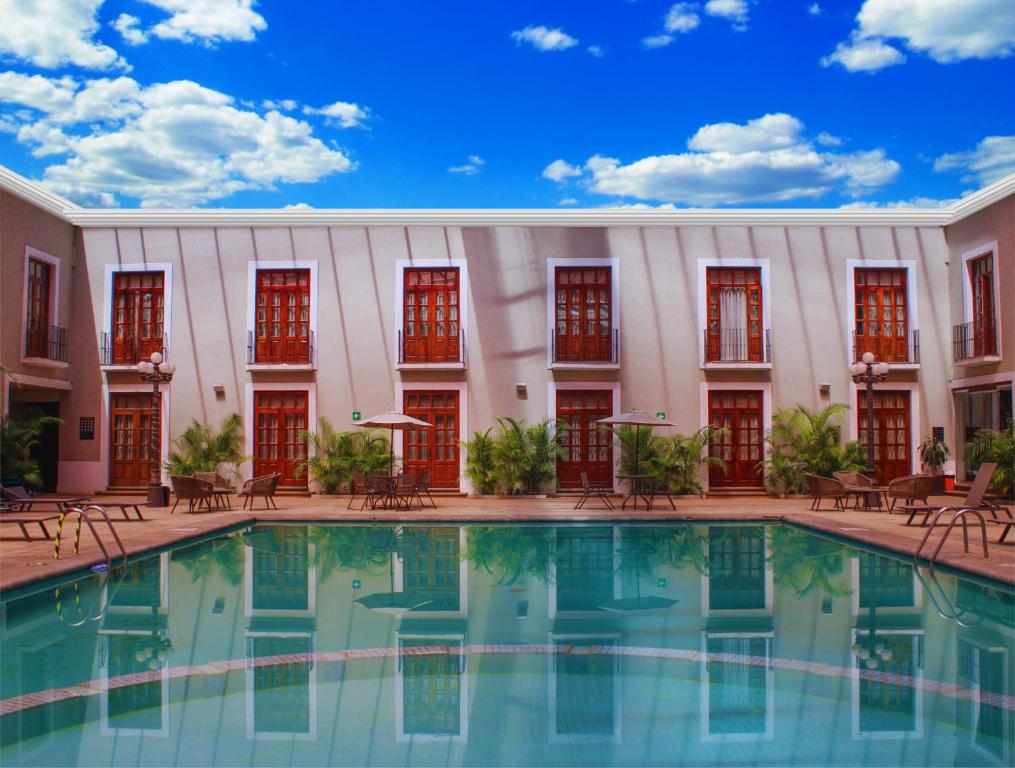 a pool in front of a building with red windows at Hotel San Francisco Tlaxcala in Tlaxcala de Xicohténcatl