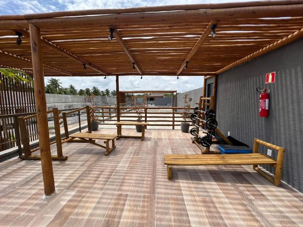 a deck with wooden benches on a building at Essence Beira mar - Porto de pedras A104 in Pôrto de Pedras