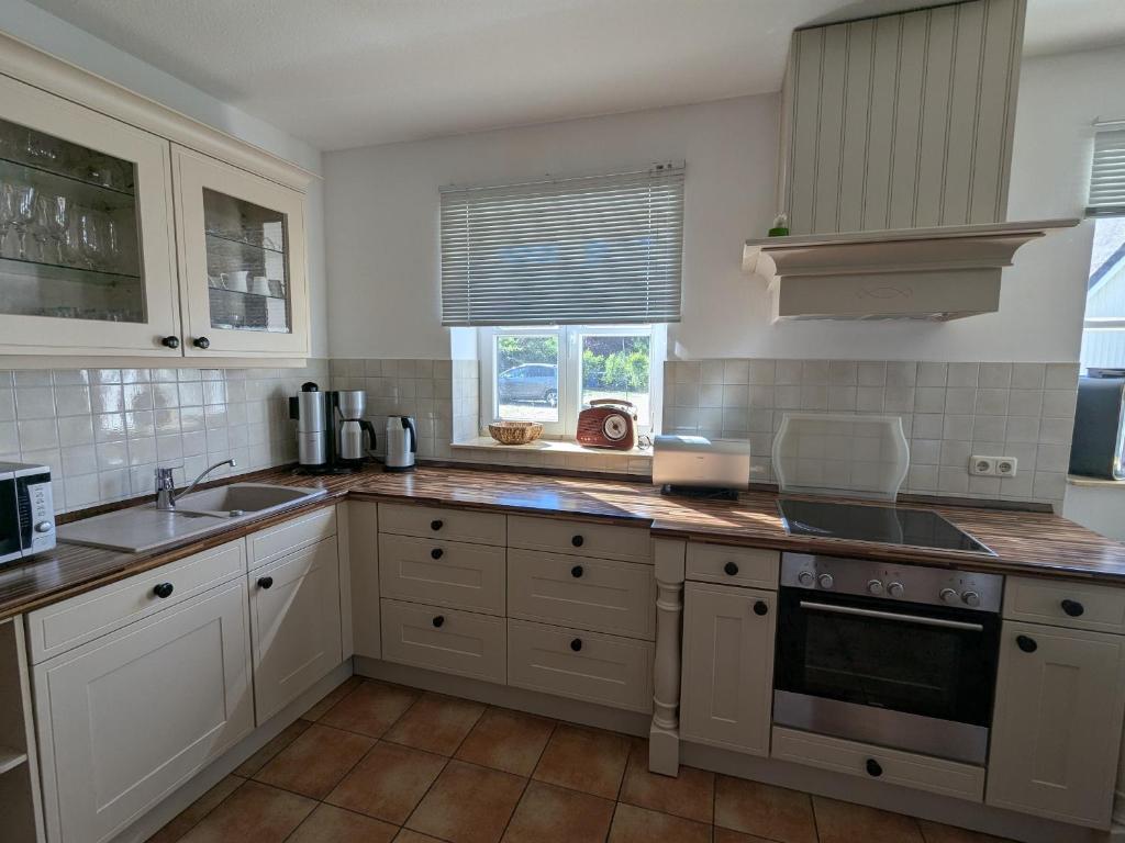 eine Küche mit weißen Schränken und einer Spüle in der Unterkunft Haus Sonne in Born