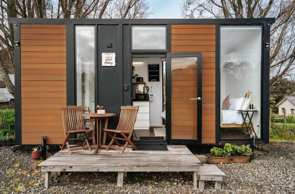 a tiny house with two chairs and a table at Kiwi Farm Cabin 1 by Tiny Away in Waitoki