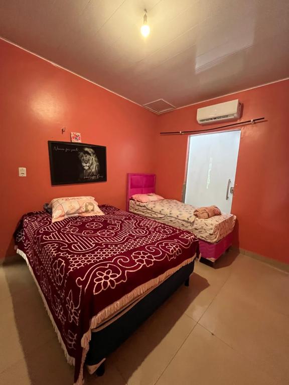 two beds in a room with red walls at Casa no Aspha Ville em Ananindeua in Ananindeua