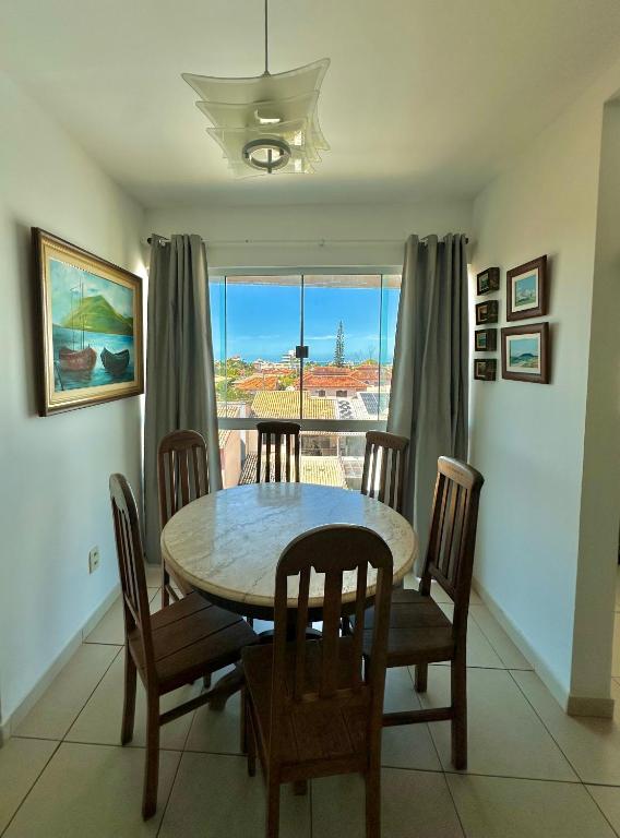 a dining room with a table and chairs and a window at Costazul Confort Flats in Rio das Ostras