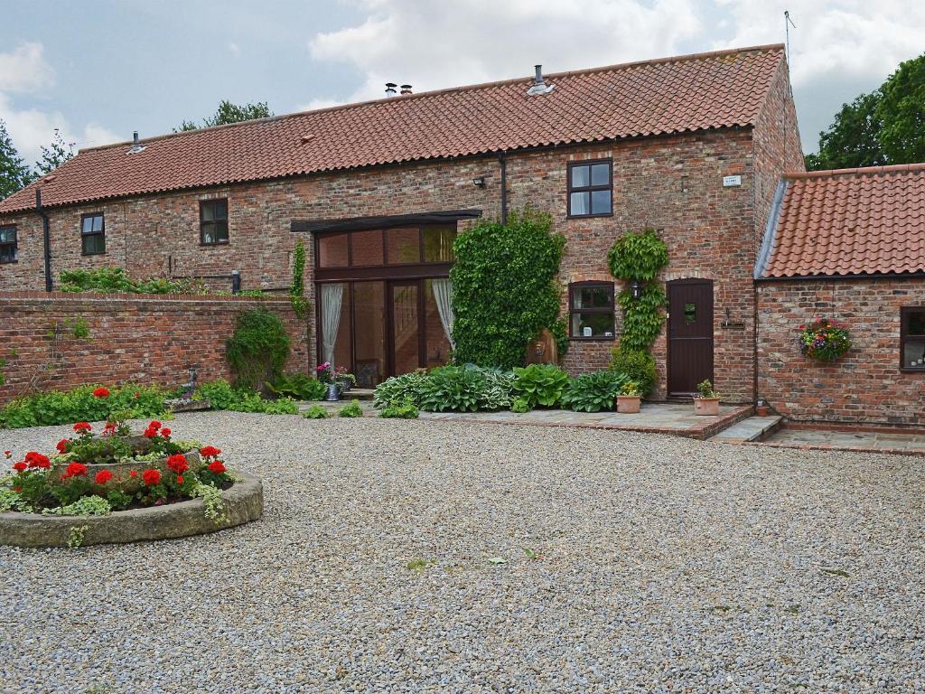 a brick house with a flower bed in front of it at The Landings Cottage in Nun Monkton