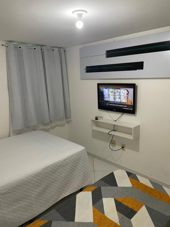 a bedroom with a bed and a flat screen tv at Mar e sol residencial 2 quartos com ar condicionado,500 metros da praia de Jacumã in Conde