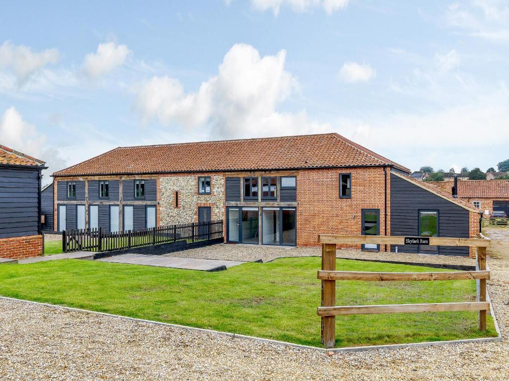 a brick house with a fence in front of it at Skylark Barn-Uk31354 in Swaffham