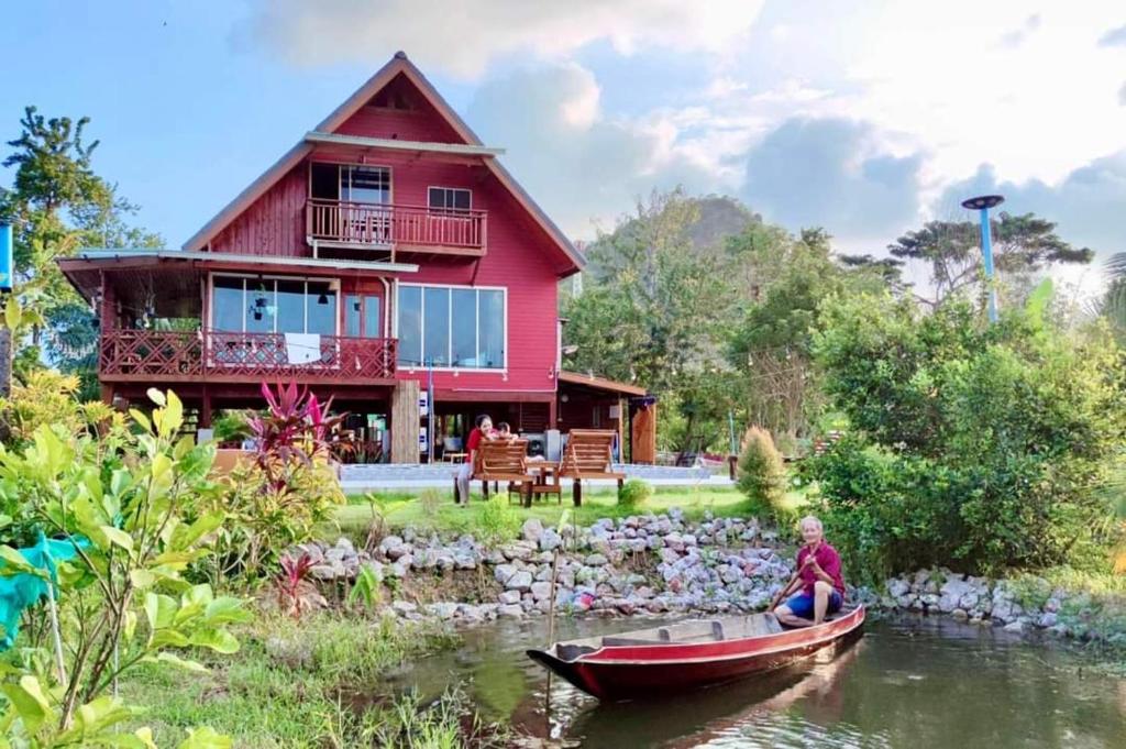 a person in a boat in front of a house at ในสวนรัตนมณีรีสอร์ท in Phatthalung
