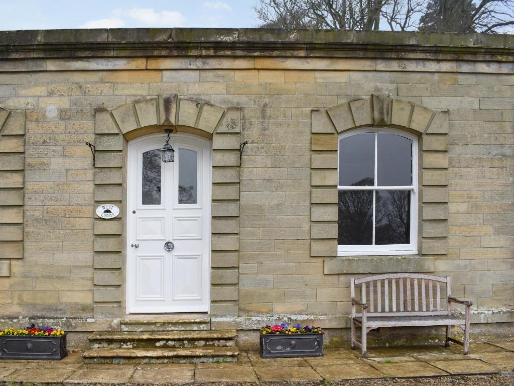 a brick house with a white door and a bench at West Lodge in Barnard Castle