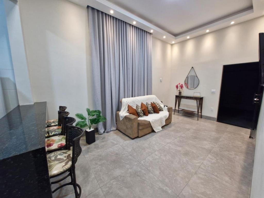 a living room with a couch and a television at Casa Alves Aluguel de Temporada Próx Hospital do Amor em Barretos SP Com Suíte e Ar condicionado in Barretos