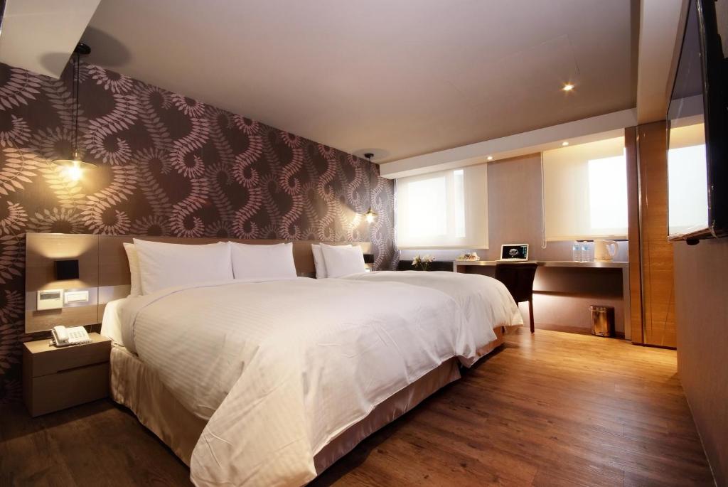 a bedroom with a large white bed and a desk at Guest Hotel in Taipei