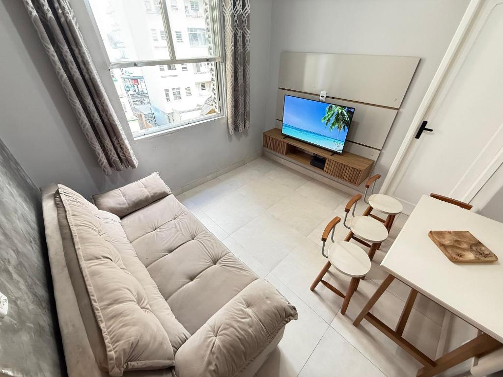 a living room with a couch and a tv at Pé na Areia Praia do Gonzaguinha II in São Vicente