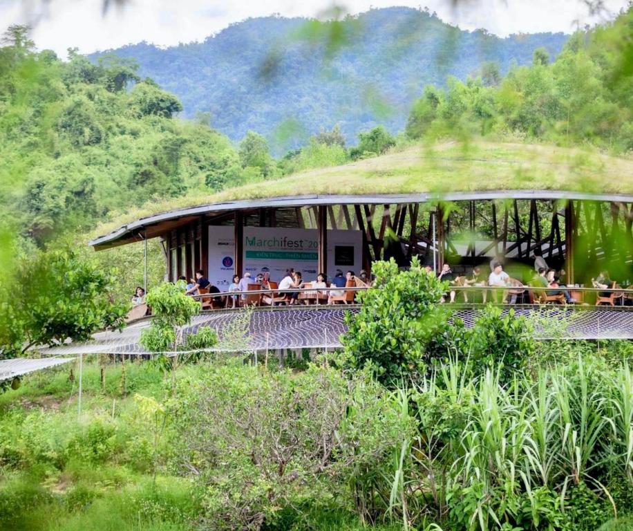 un gruppo di persone sedute in un edificio con un tetto d'erba di Làng Nhỏ - Hồ Láng Nhớt Resort with Nature Life a Nha Trang
