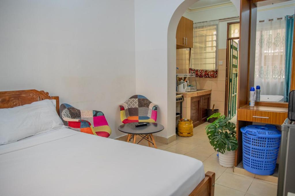 a bedroom with a bed and two chairs at Serene Apartments - studio 001 in Mombasa