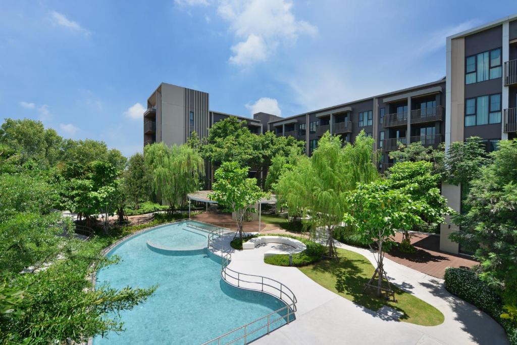 A landscaped pool curves through the hotel garden beneath a bright blue sky.