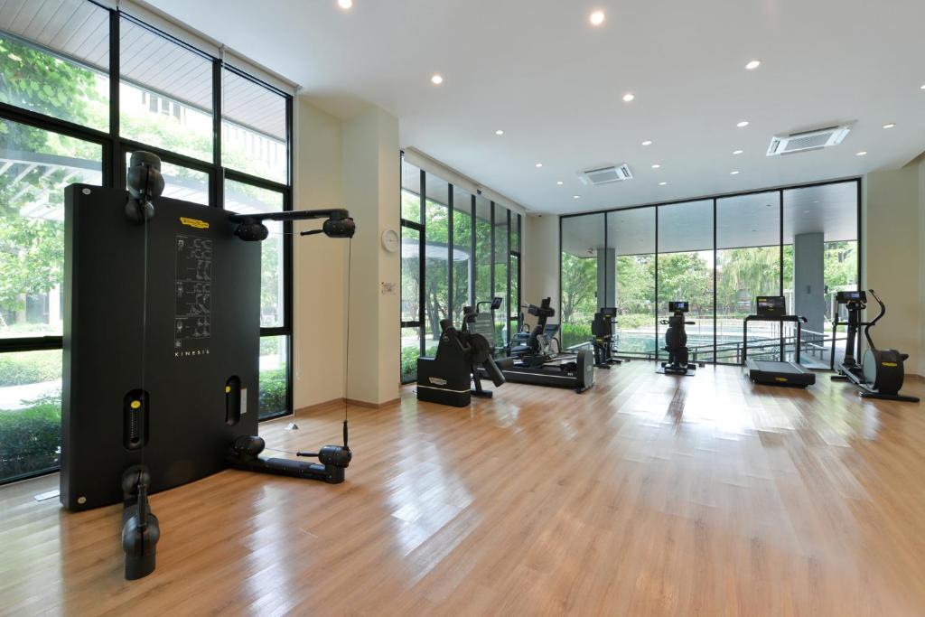 A bright fitness room combines cardio equipment with a cable machine and garden views.