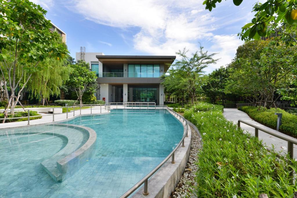 A landscaped outdoor pool curves toward a modern building and garden paths.