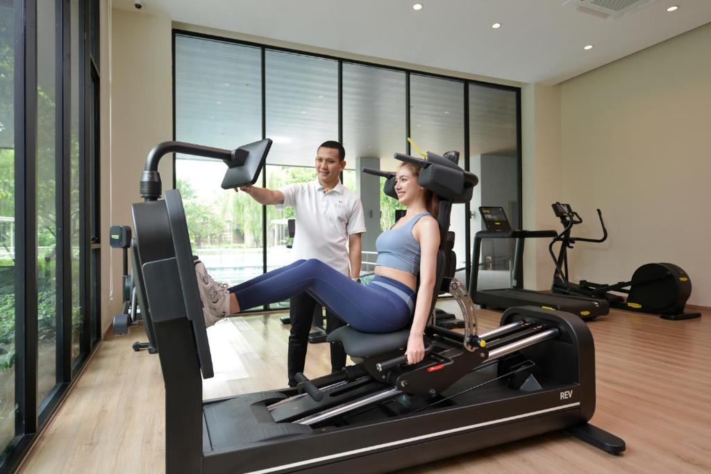 A bright gym with strength-training equipment and cardio machines beside full-height windows.