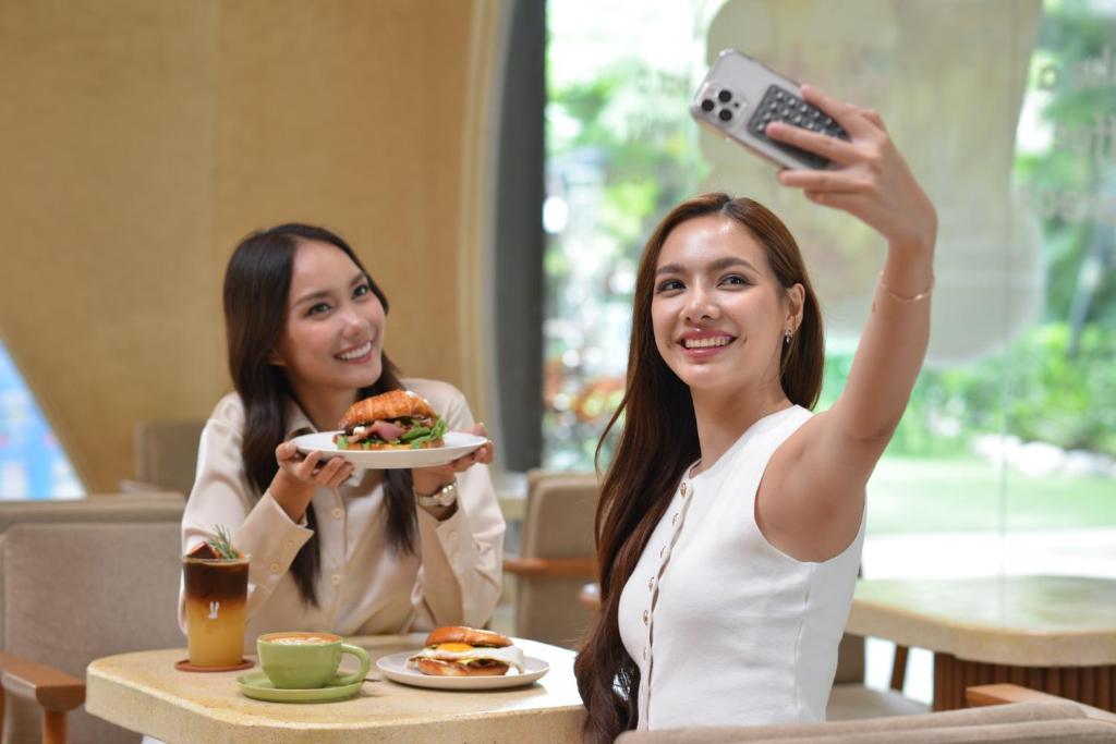 A bright dining area where two guests are enjoying plated food beside tall windows.