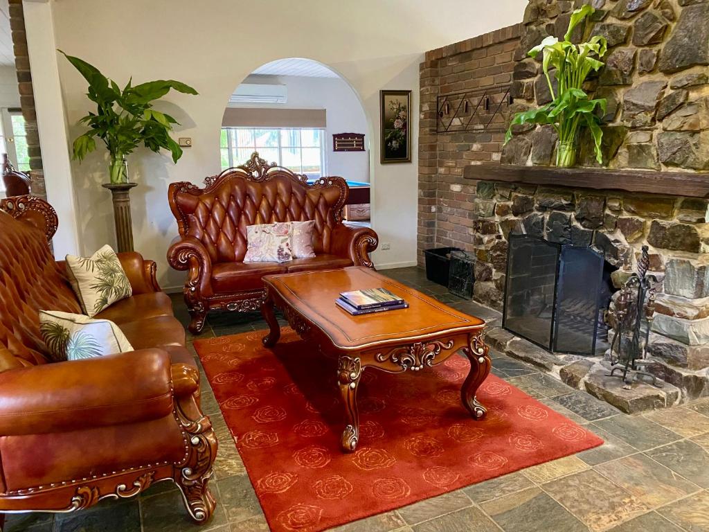 a living room with leather furniture and a stone fireplace at Mornington Peninsula Farmhouse in Main Ridge