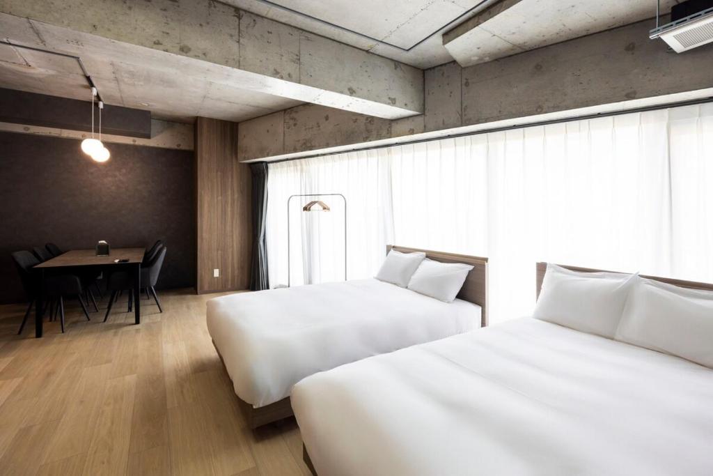 a hotel room with two beds and a table with a tableablish at Amp Flat Arc Bliss 3 in Chikushino