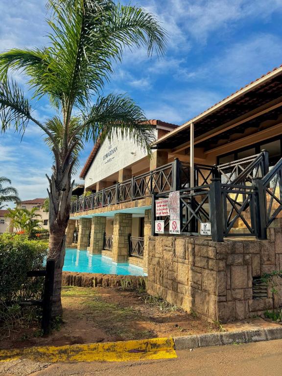 a resort with a palm tree and a swimming pool at Ocean View Villas F05 in Port Edward