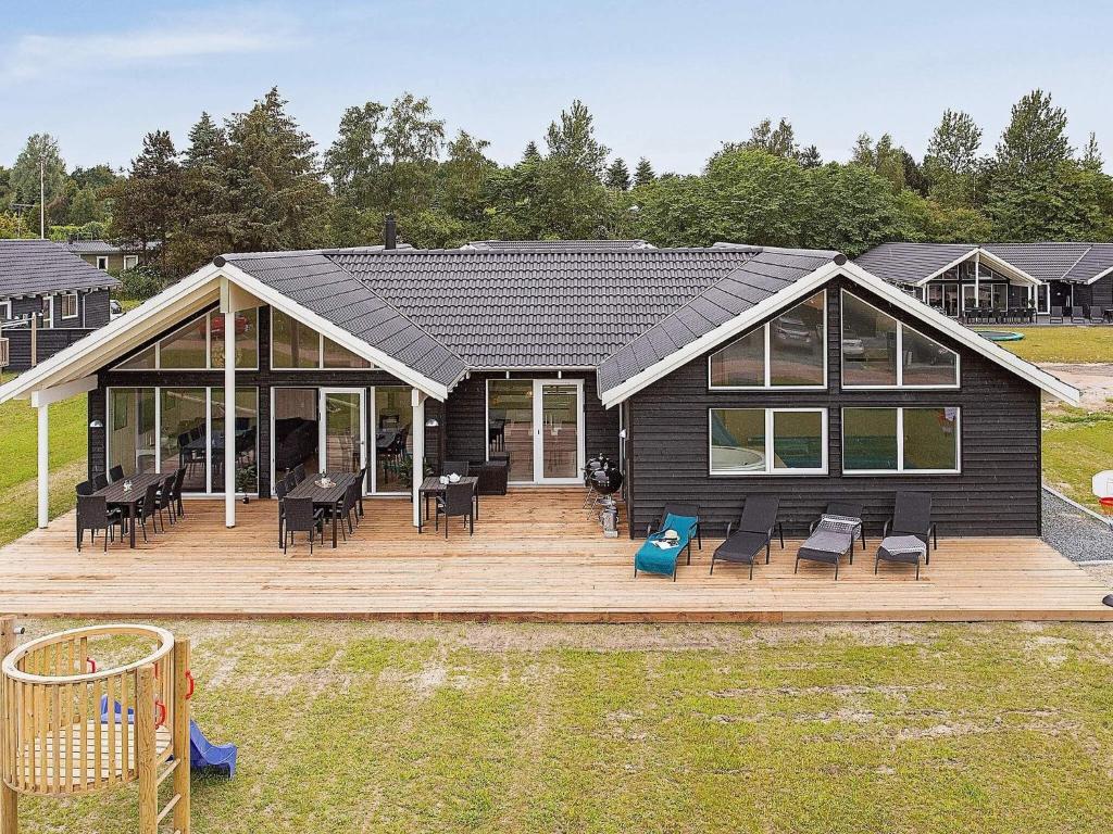 uma casa com um deck com cadeiras e um playground em 16 person holiday home in Vejby em Vejby
