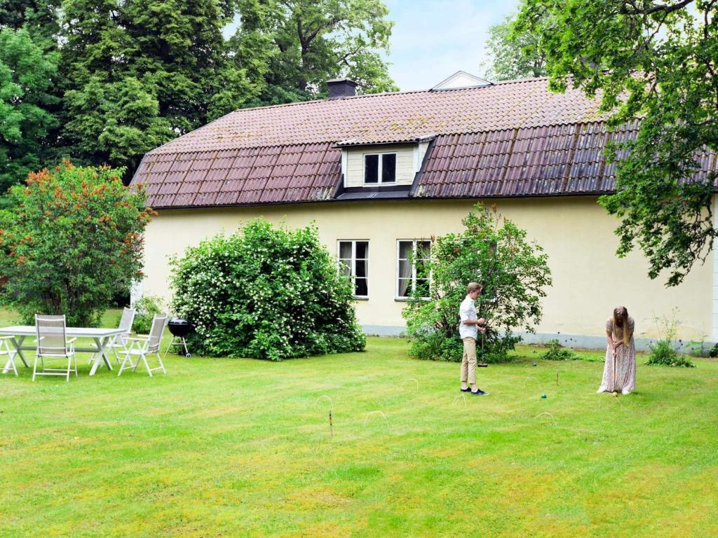 two people standing in the yard of a house at 11 person holiday home in STORA SUNDBY in Böcklinge