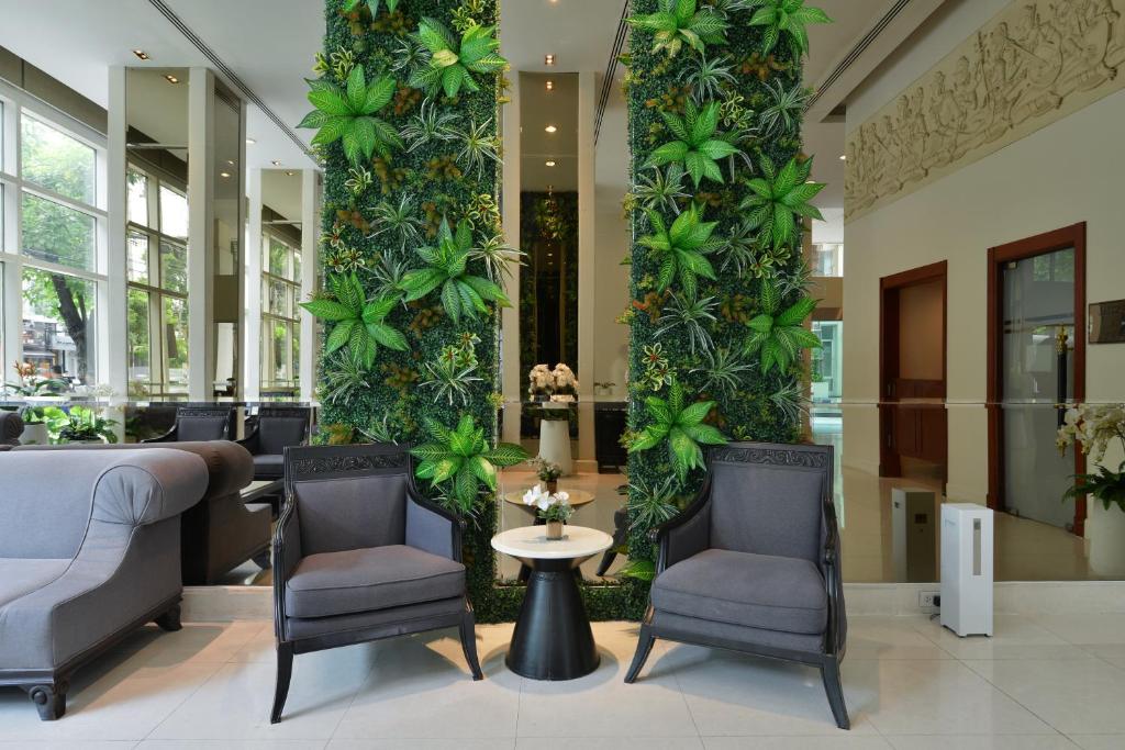 A lobby seating nook framed by tall indoor foliage and mirrored columns.