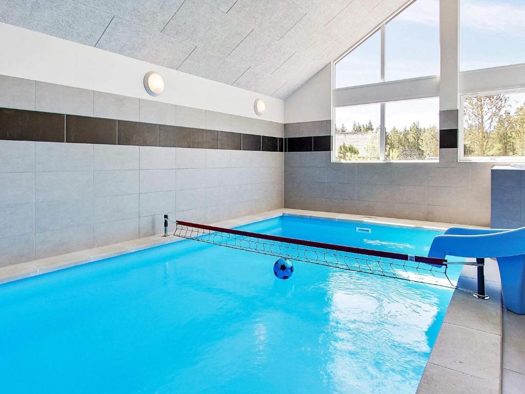 - une piscine d'eau bleue dans une chambre avec fenêtres dans l'établissement Luxury Retreat in Blavand - By Traum Ferienwohnungen, à Blåvand