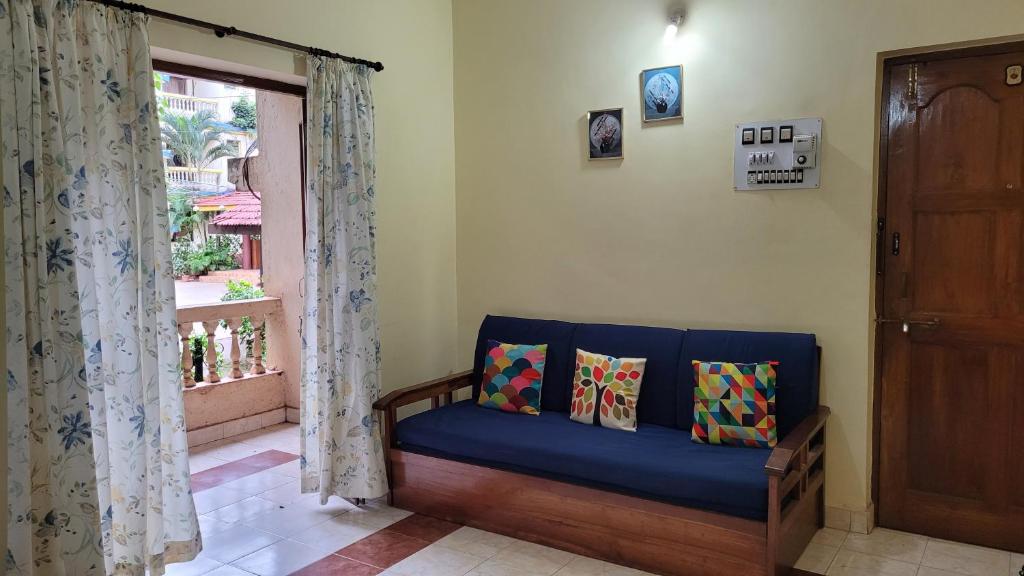 a living room with a blue couch and a window at THE 101 HOMESTAY, Calangute by ROSH HOSPITALITY in Calangute