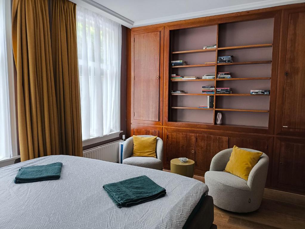 a bedroom with a bed and two chairs and a shelf at Blue Wave Stay - Free Parking in Scheveningen