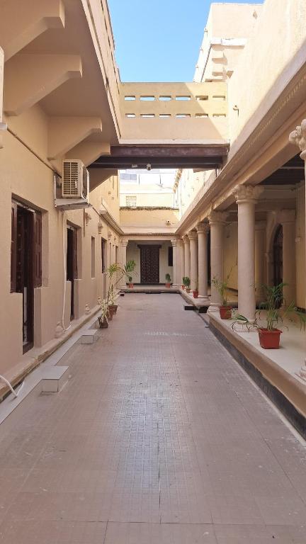 an empty hallway of a building with columns and plants at The Imperial Regency in Porbandar