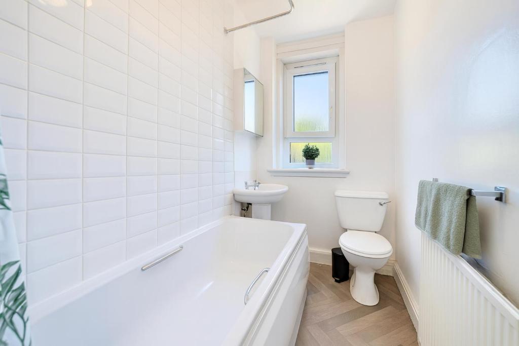 een witte badkamer met een bad en een toilet bij Walk to Hydro and SEC Modern 3BR Free Parking in Glasgow