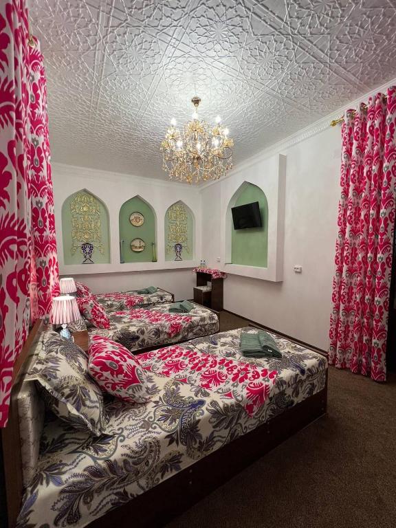 two beds in a room with a chandelier at Zardozon Hotel in Bukhara